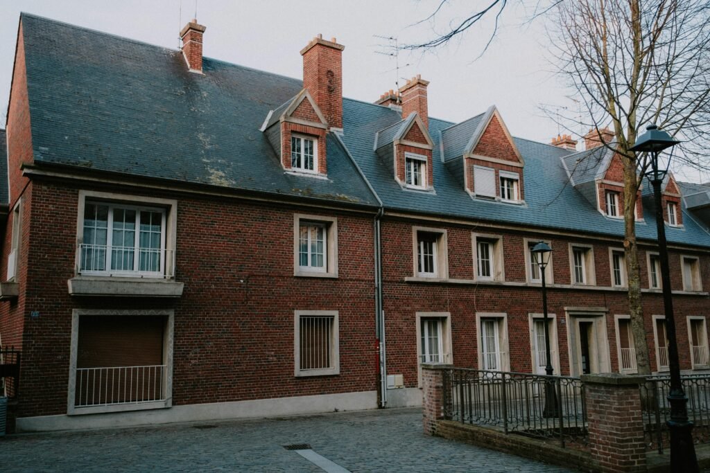 A classic brick building with dormer windows and chimneys under a tranquil sky.