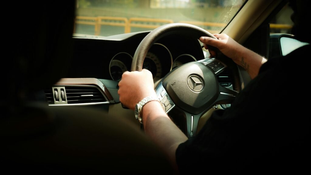 Close-up of a driver steering a Mercedes-Benz through Bengaluru, India.