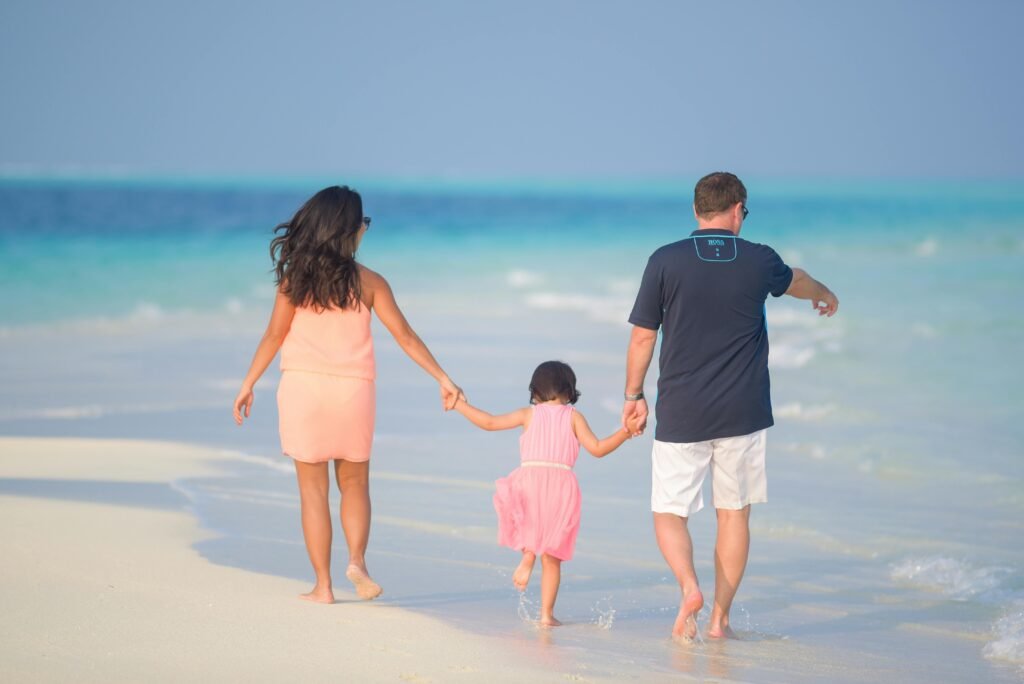 A joyful family walking hand in hand along a sunny beach, capturing moments of togetherness.