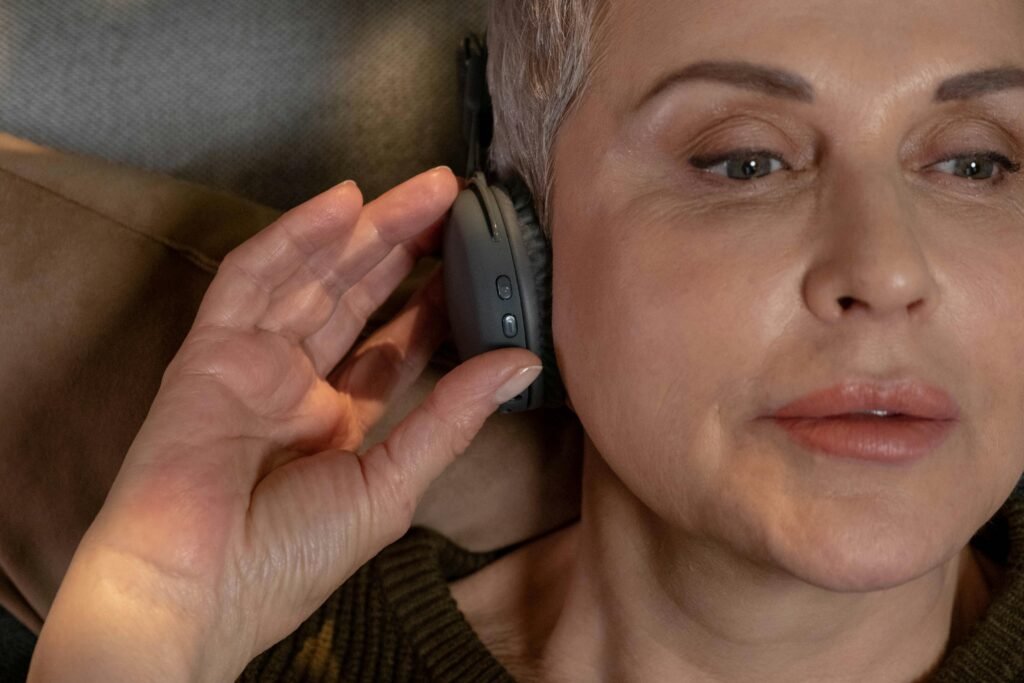 Close-up of an elderly woman listening to music with headphones, highlighting serenity.