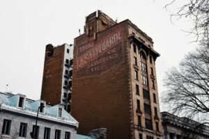 Old brick building with faded vintage signage. Clear urban winter scene.