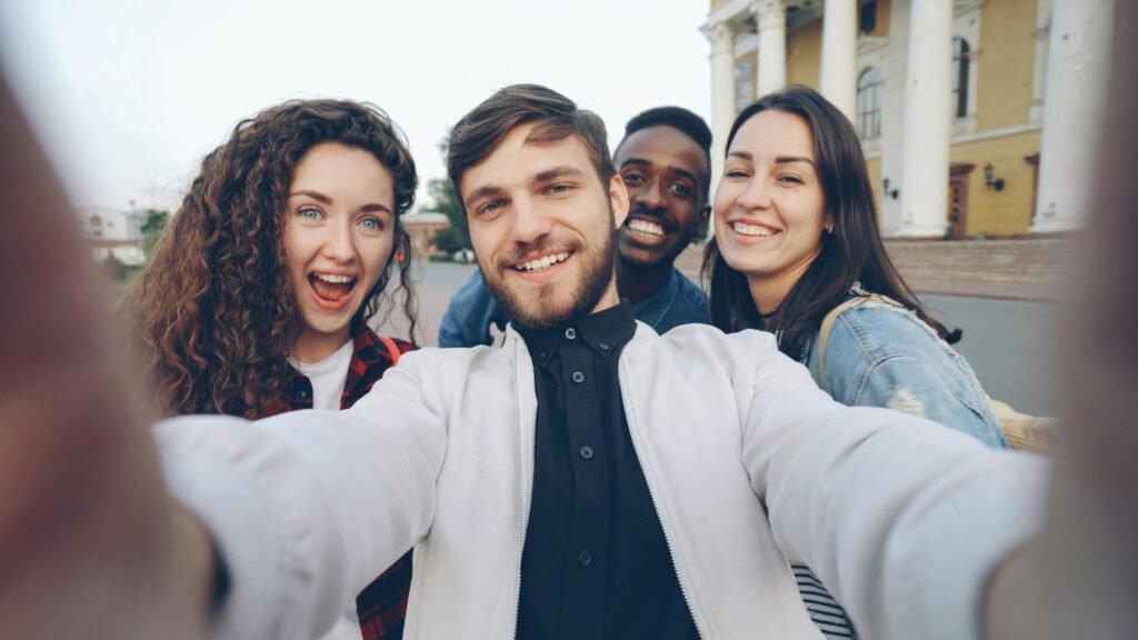 Friends taking a joyful selfie outdoors with a historic building in the background.