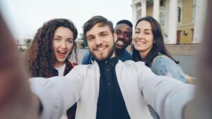 Friends taking a joyful selfie outdoors with a historic building in the background.