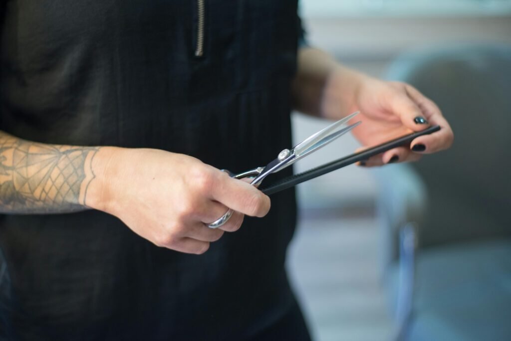 Assurance Salon de Coiffure et Esthétique : Le Guide de l'Expert à Arras A hairdresser's hands holding scissors and a comb in a salon setting.