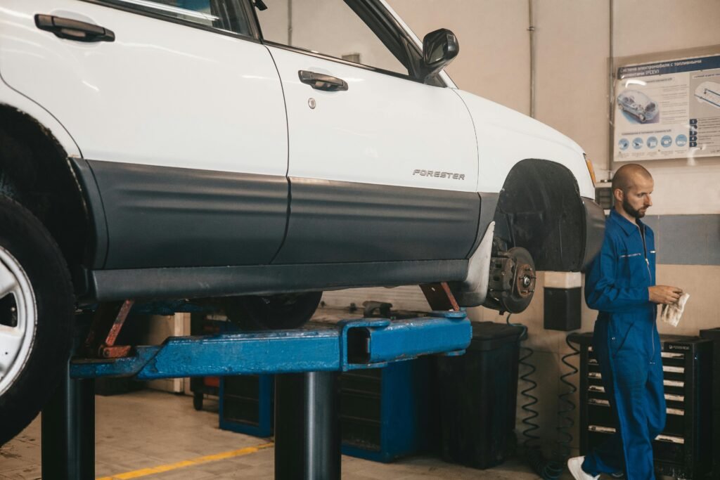 Mechanic evaluating a car on a lift for maintenance in an auto workshop.